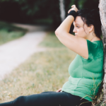 žena v zelenom – opretá o strom